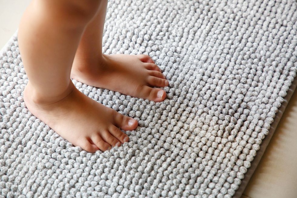 A child's feet standing on a bath mat