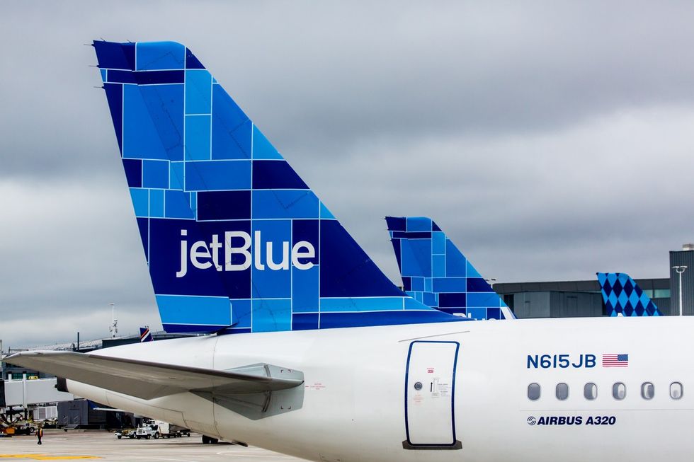 A close up of a JetBlue plane's tail fin while parked at an airport