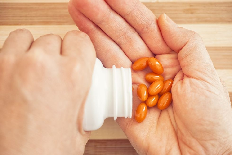 A close up of someone pouring CoQ10 supplement capsules into their hand