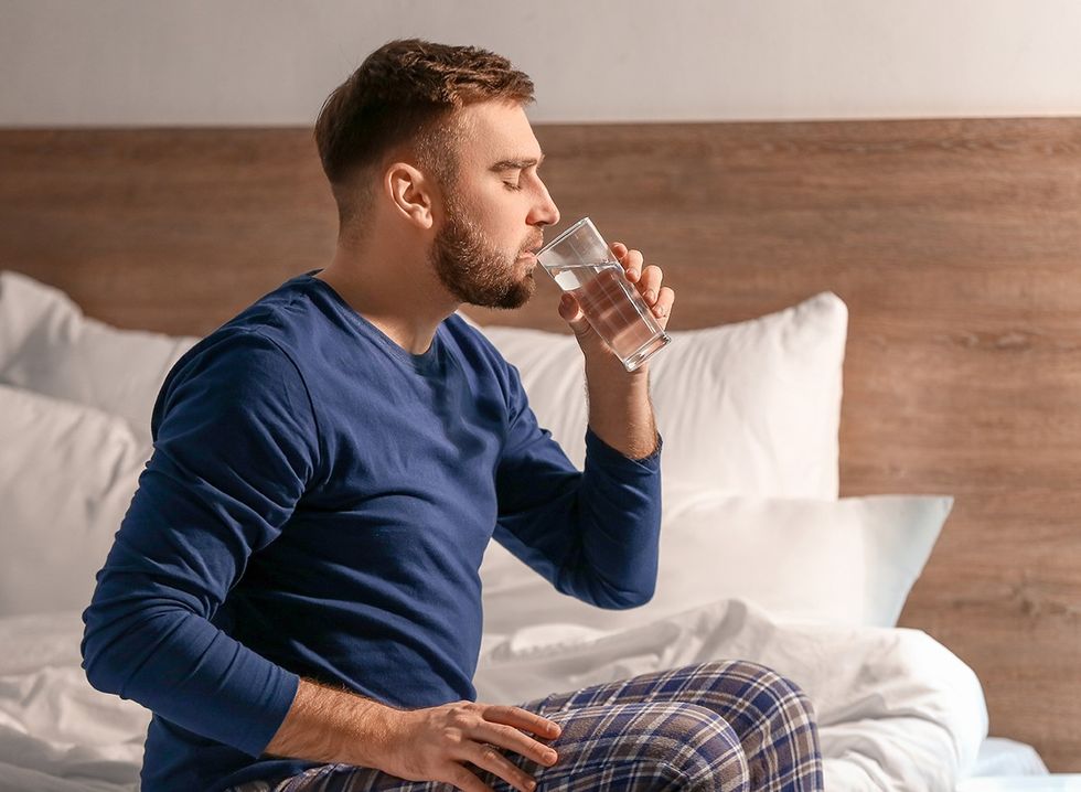 A man drinking a glass of water before going to bed