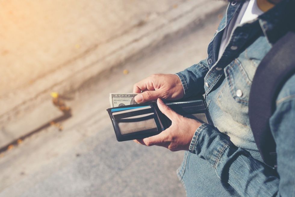 A man holding a wallet containing cash