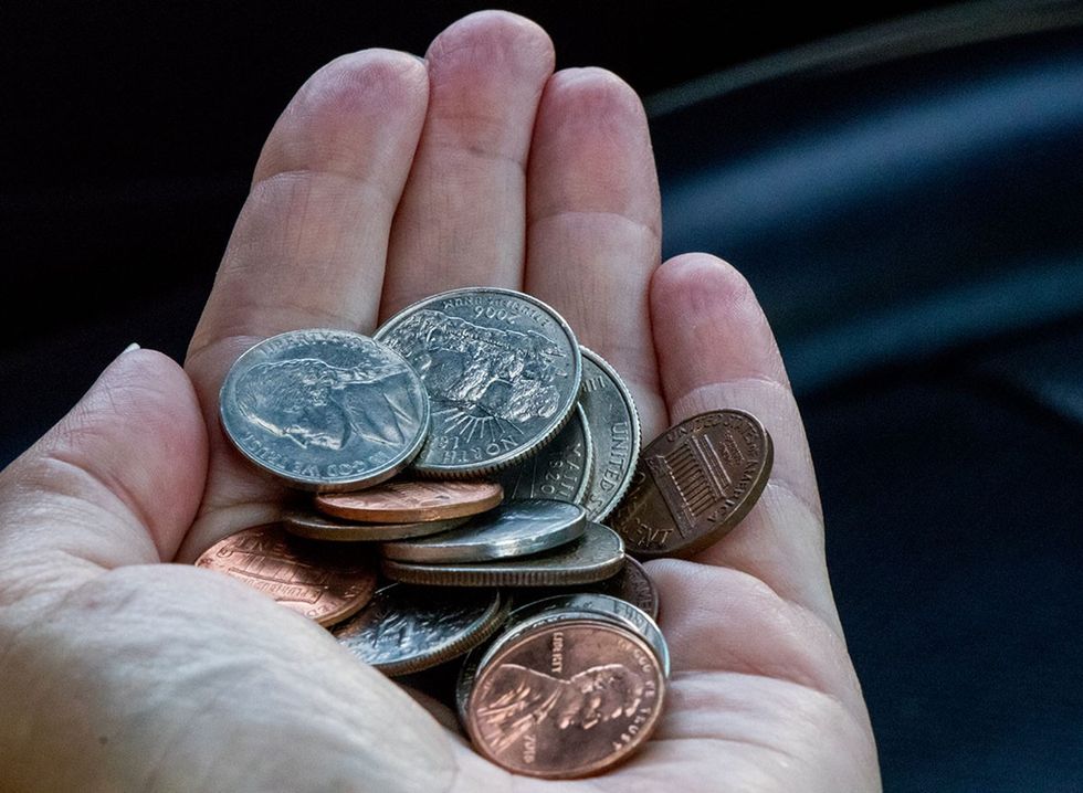 A man's hand holding coins