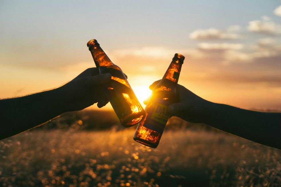 a pair of friends share a beer together at sunset