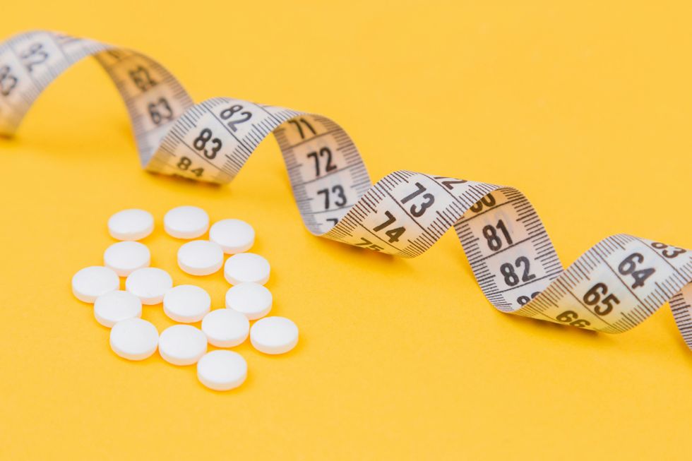 a series of vitamins against a white background and measuring stick