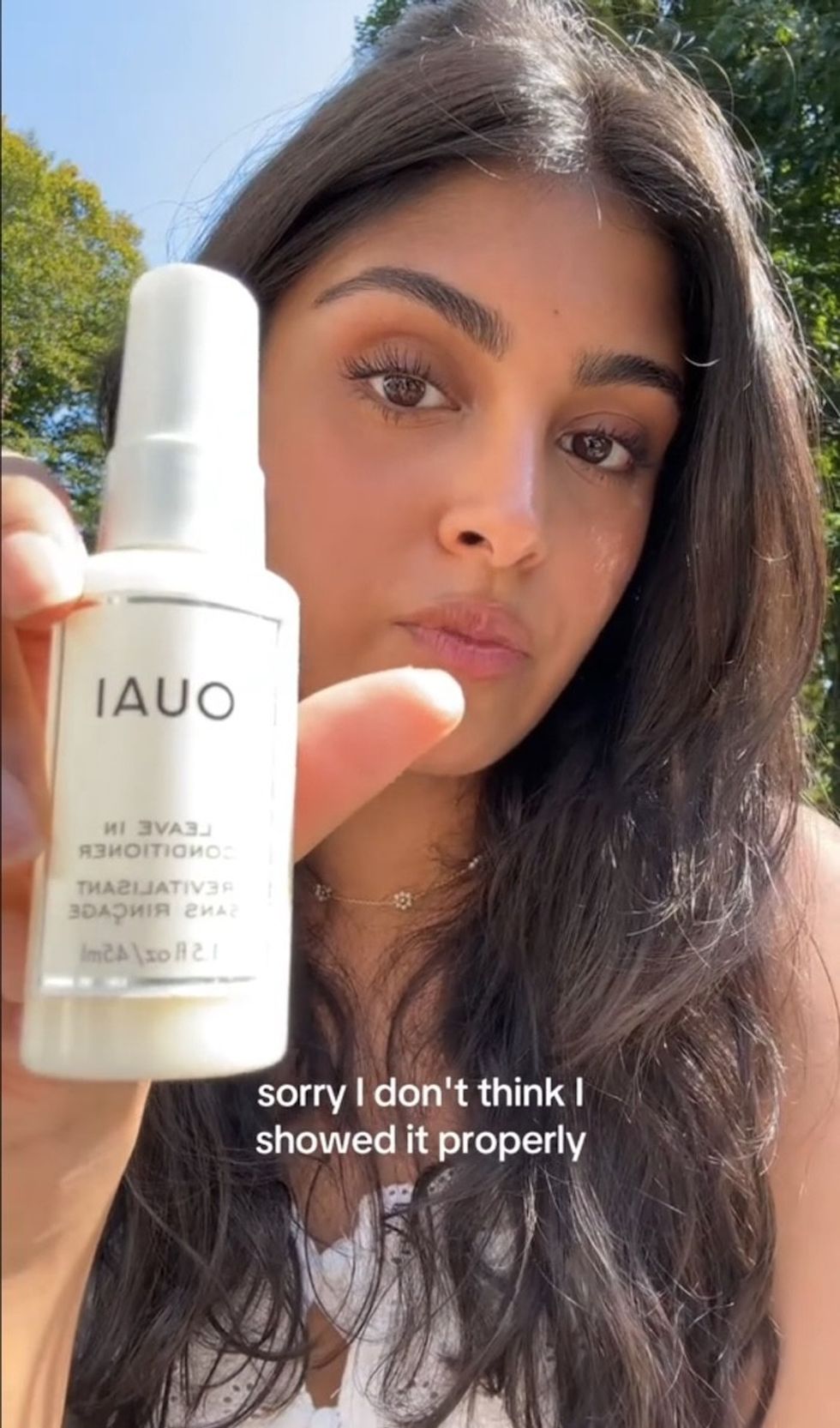 A TikToker holding up Ouai Leave-In Conditioner