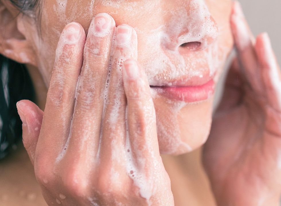 A woman washing her face with facewash