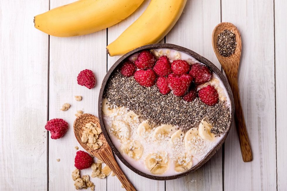 bowl of yogurt with bananas, raspberries, and chia seeds