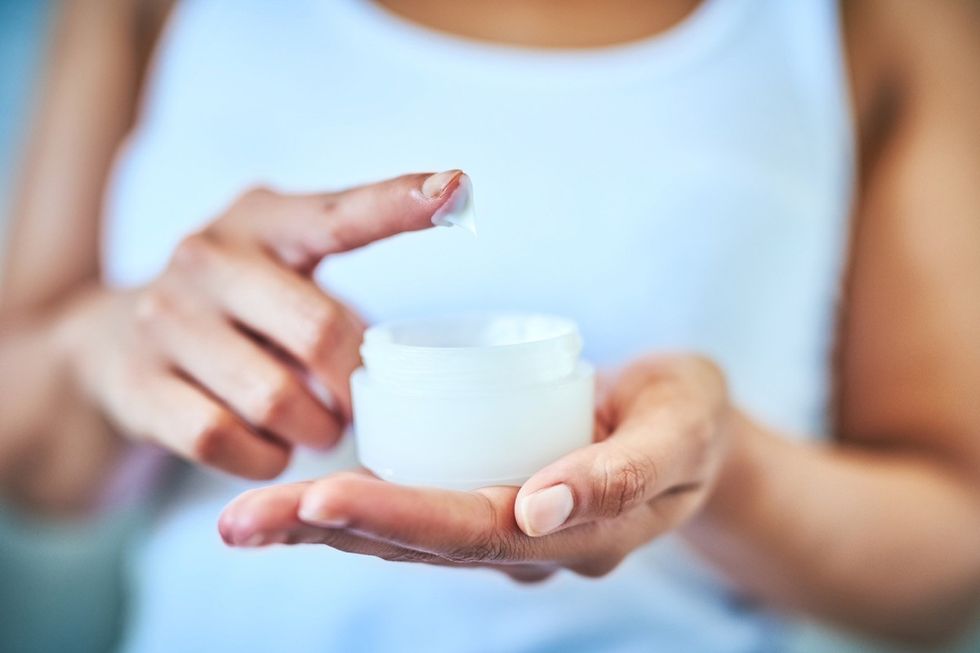 close up of woman putting her finger in moisturizer