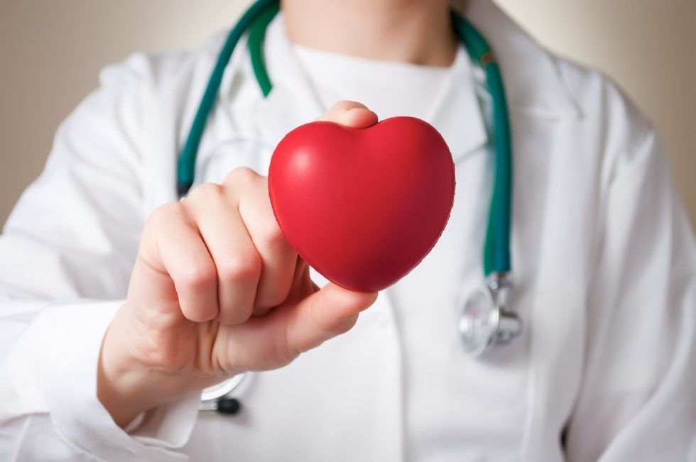 closeup of a doctor in a white coat holding a red heart