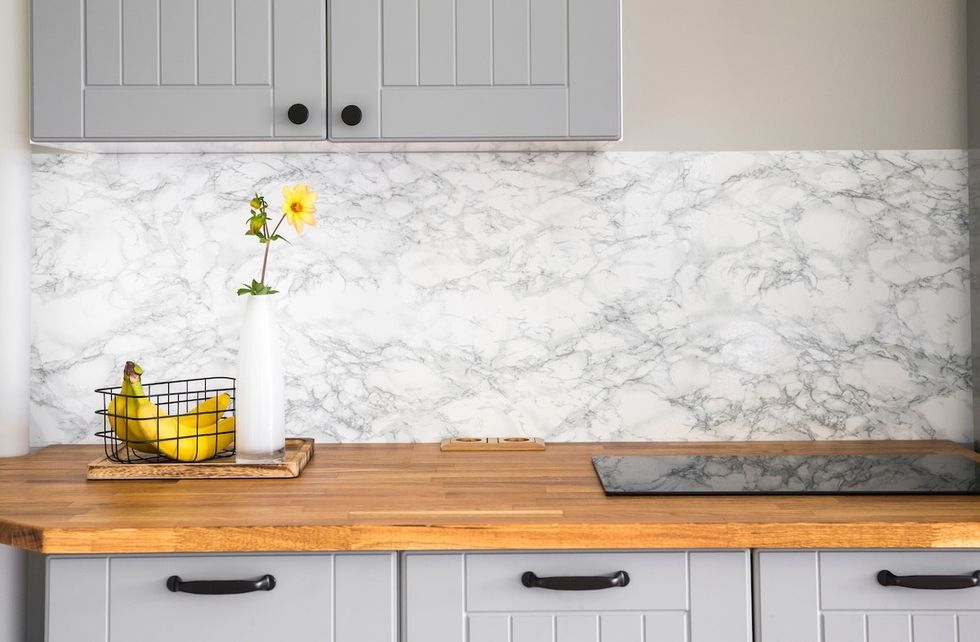 closeup of gray kitchen cabinets with wood counters and a marble backsplash