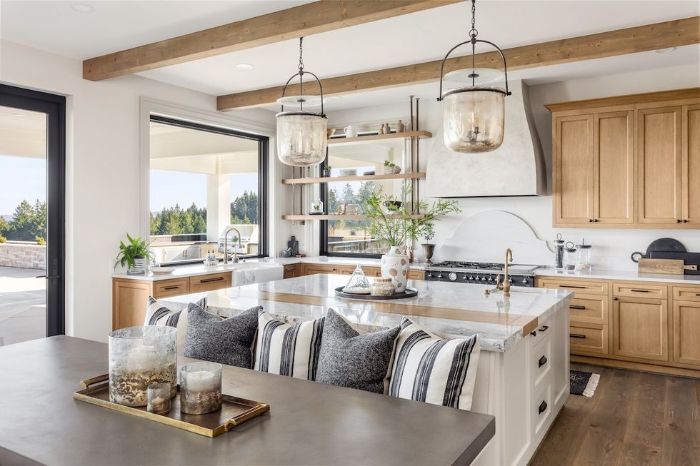 coastal-style kitchen with whites, navy blues, and woods and a large table built into the kitchen island