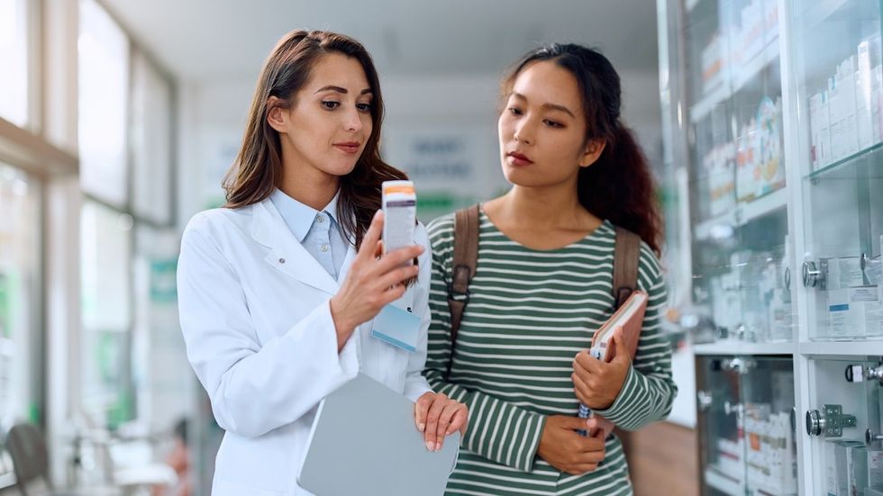 dermatologist doctor talking to a young woman with prescription in hand