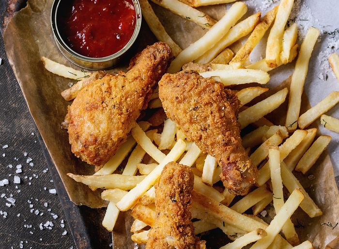 Fried chicken fingers and french fries on a tray with ketchup.