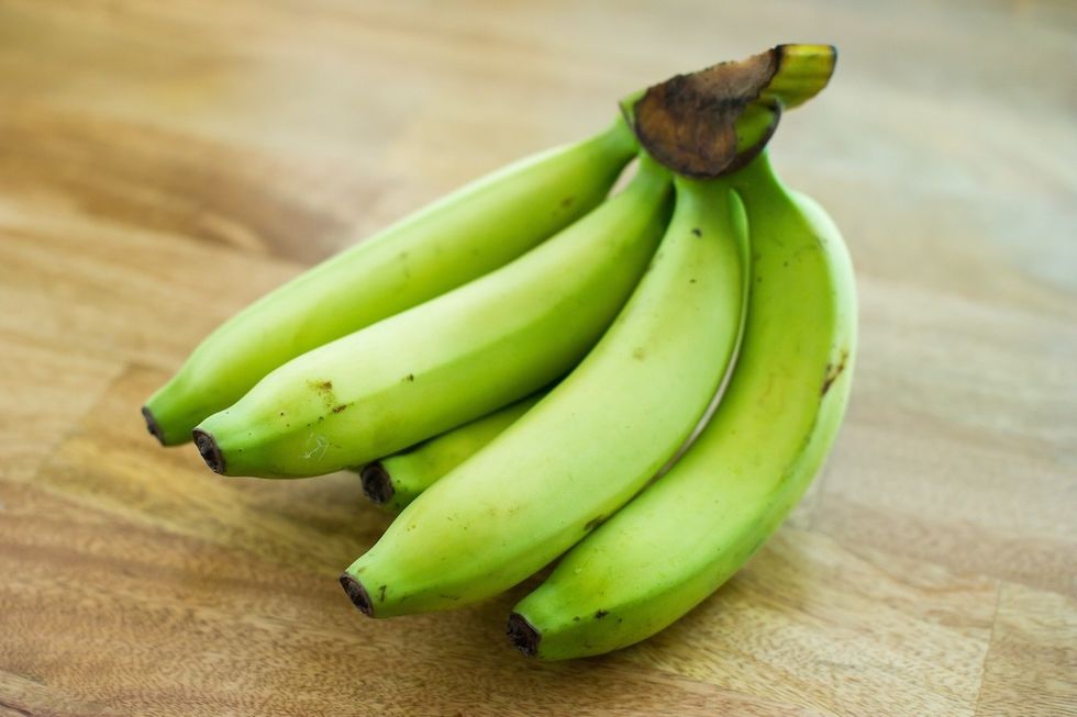 green bananas on wood surface