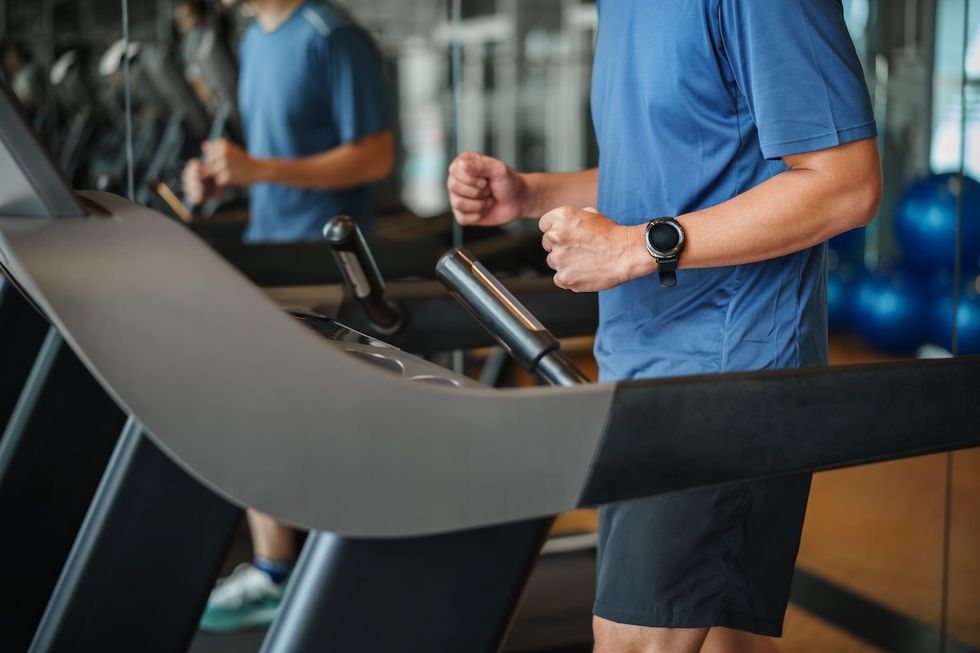 man in a blue t-shirt and black shorts on a treadmill in the gym