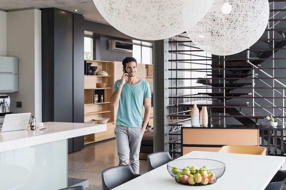 man walking through a modern kitchen talking on the phone