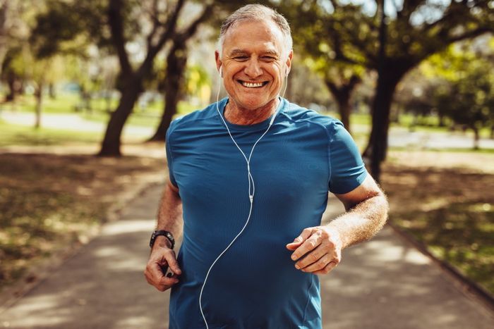 Mature man in a blue t-shirt running in a park.