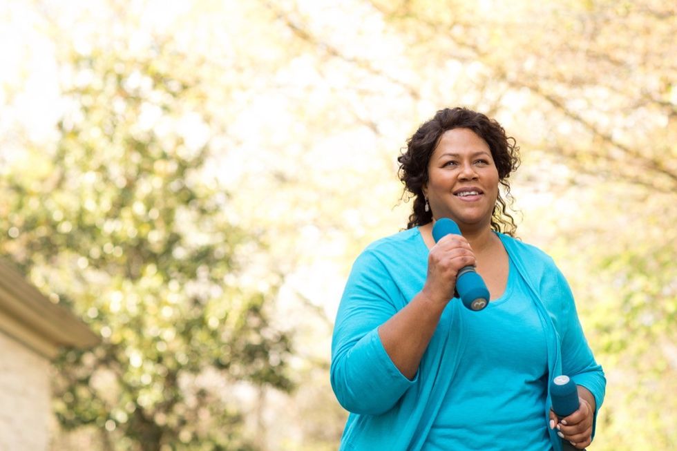 Older black woman walking and exercising with weights in her hands