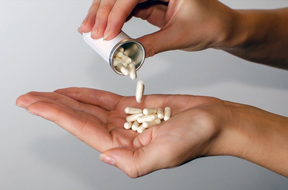 pouring supplements pills into hand