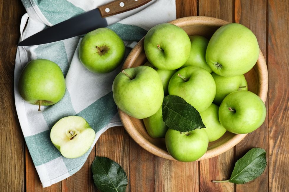 ripe green apples in bowl on table