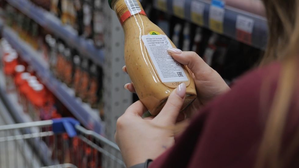 woman in grocery store holding salad dressing bottle