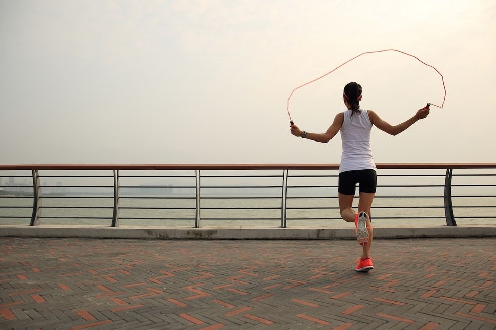 woman jumping rope alongside a waterfront promenade