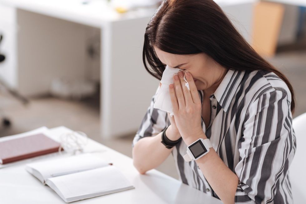 woman sneezing at desk