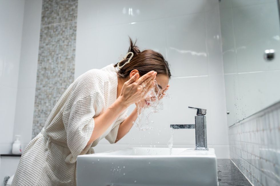 woman washing her clean face with facial foam and water.