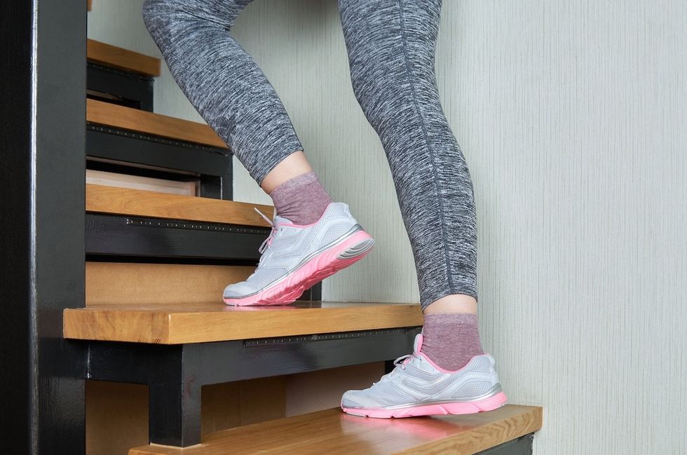 woman wearing gray leggings walking up a flight of stairs