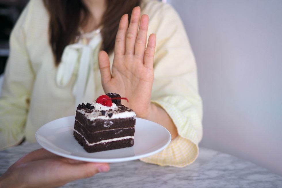 Woman with her hand out to refuse a piece of chocolate cake