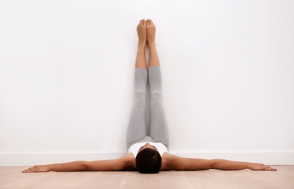 woman with her legs up the wall, working out or stretchin