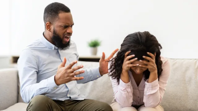 Young married black couple having fight, guy yelling at crying lady, gesturing at home.