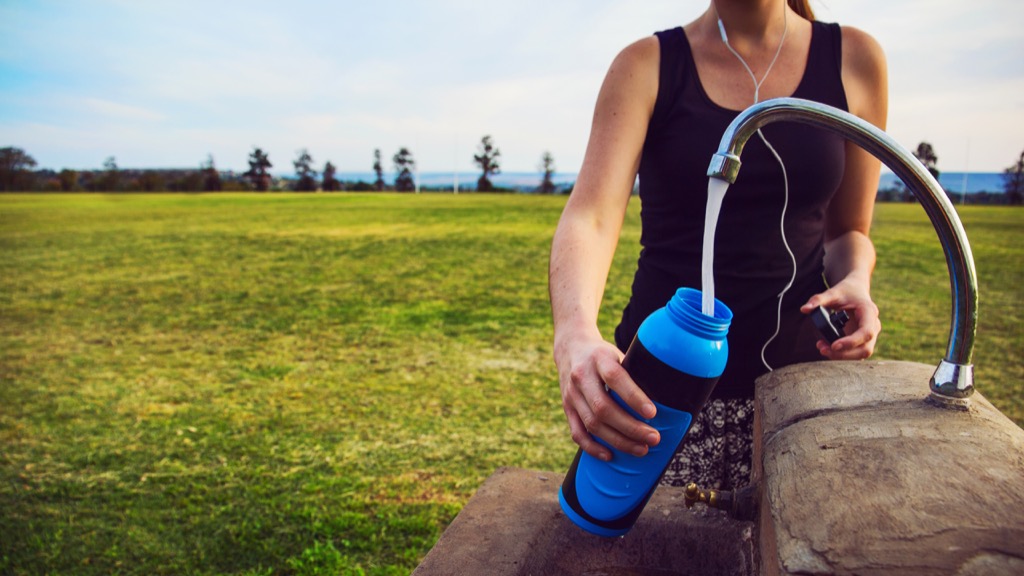 woman filling water bottle outside, weight loss motivation