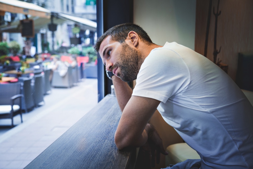 white man thinking while he leans on counter at cafe