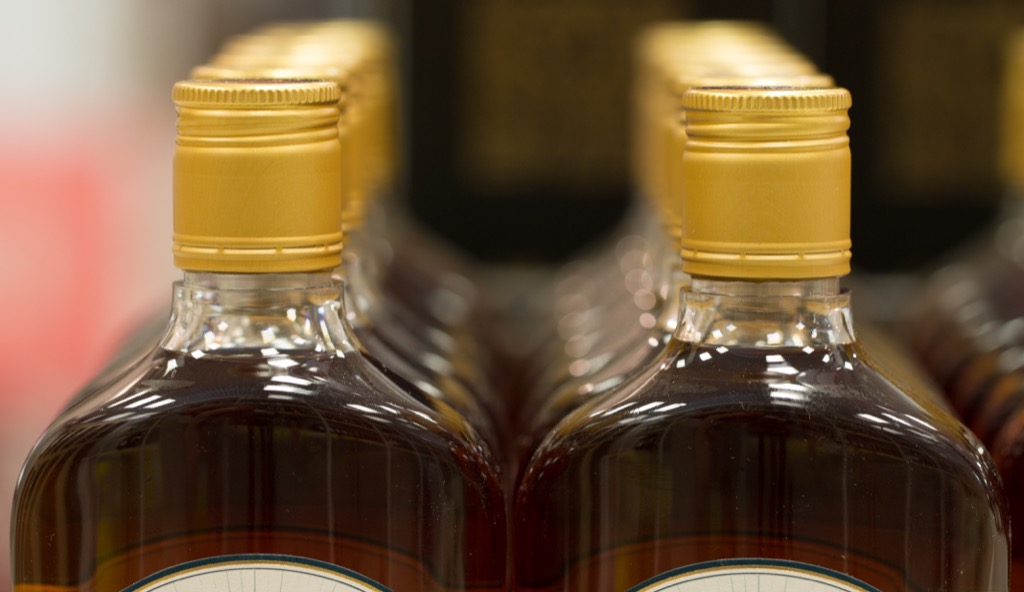 Rows of rum bottles with gold lids, state fact about Rhode Island