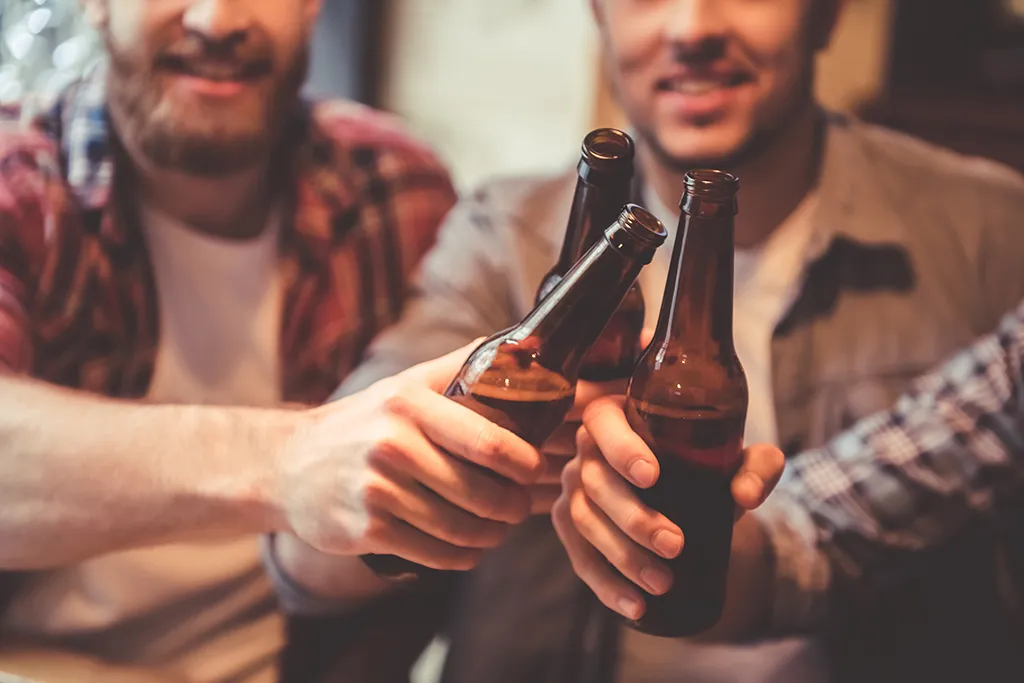 men clinking beer bottles together
