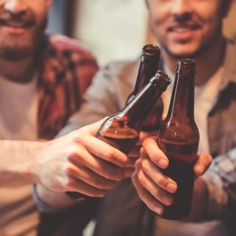 men doing a toast with beer bottles, relationship white lies