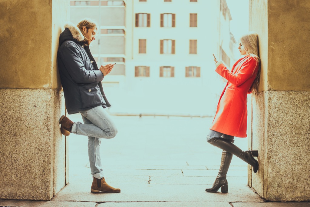 man and woman on phones in an outside archway, The best opening lines for online dating