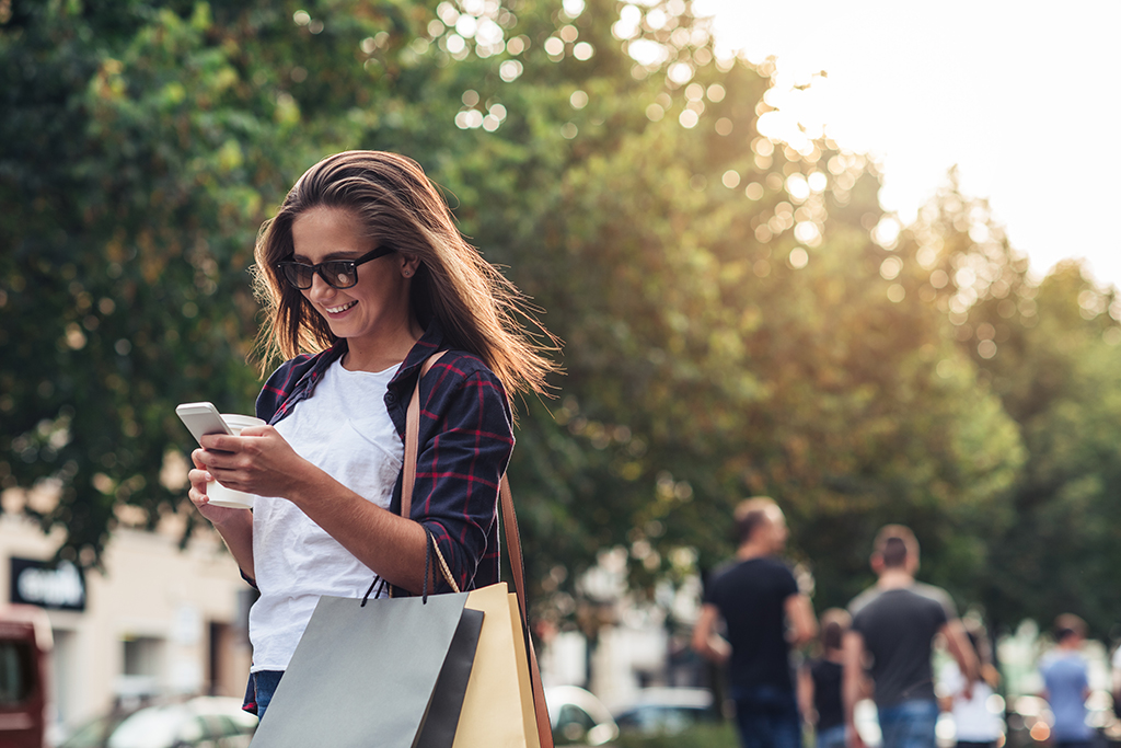 woman holding shopping bags and looking at her phone, The best opening lines for online dating
