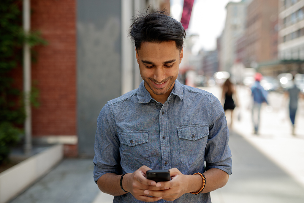 man looking at his phone and smiling, The best opening lines for online dating