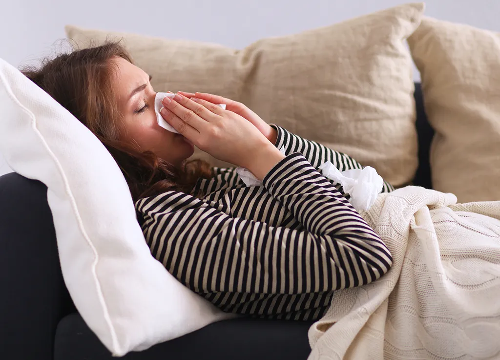 woman sneezing on couch - being single