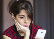 woman looking at phone, things not to say to customer service