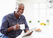 man holding coffee smiling with breakfast
