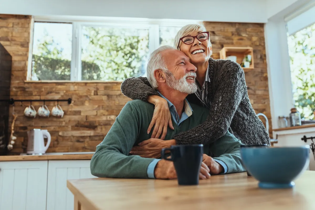 older couple hugging and smiling in the kitchen