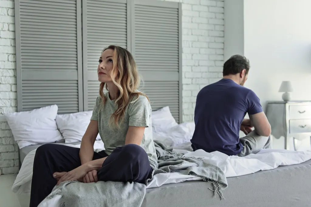 Two people going through a divorce, sitting on bed