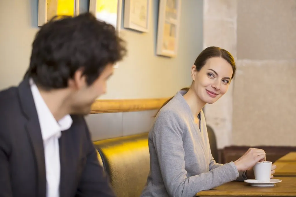 woman looking at a man at a coffee shop, how to tell if a girl likes you 