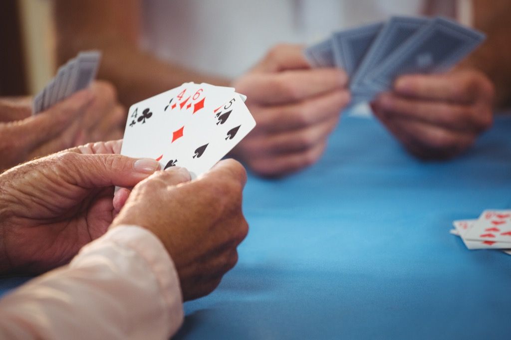 close up of hands playing cards at a card table