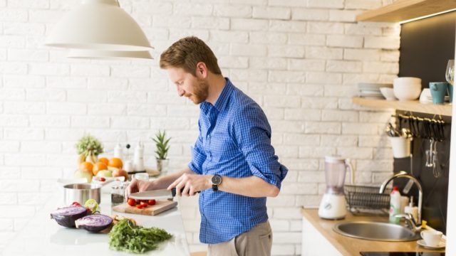 man in blue button down shirt cooking food in modern kitchen