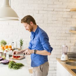 man in blue button down shirt cooking food in modern kitchen