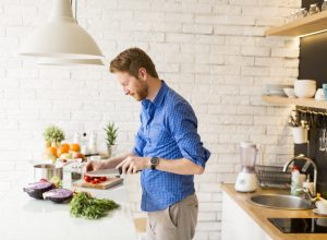 man in blue button down shirt cooking food in modern kitchen